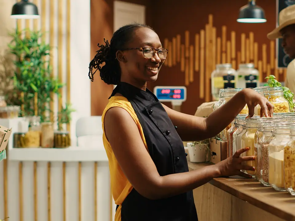 A shop owner serving from glass jars