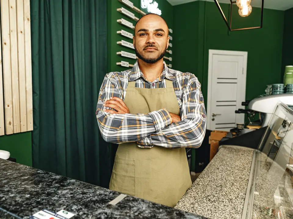A shop owner in an apron, arms folded