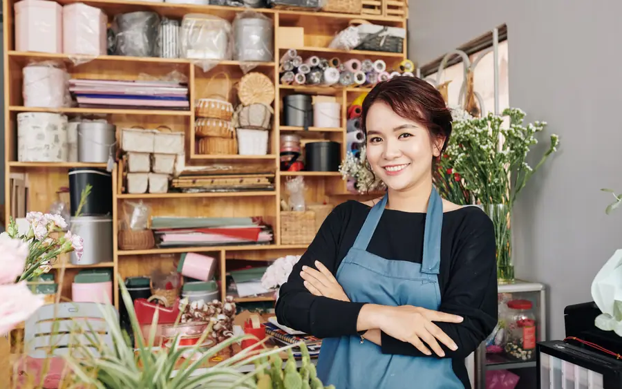 A shop owner among her shelves, arms folded
