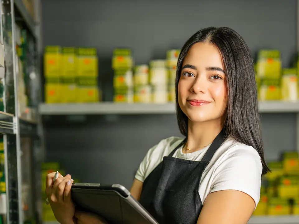 A shop owner with a tablet among her shelves