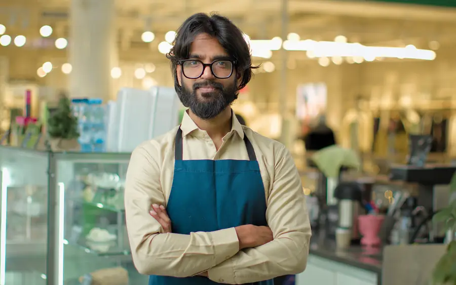 A shop owner in an apron, arms folded
