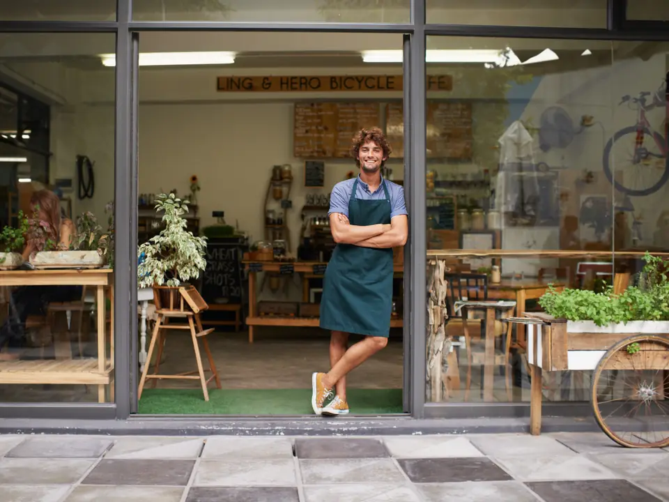 A café owner in the open doorway of his shop